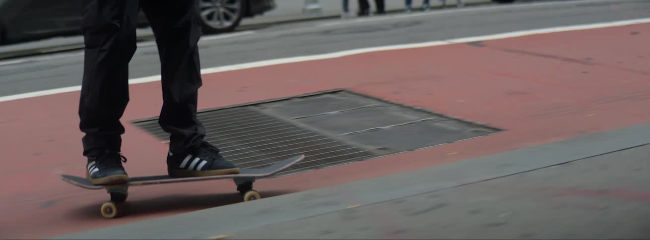 Man riding a skateboard on the city street near parked cars at daytime
