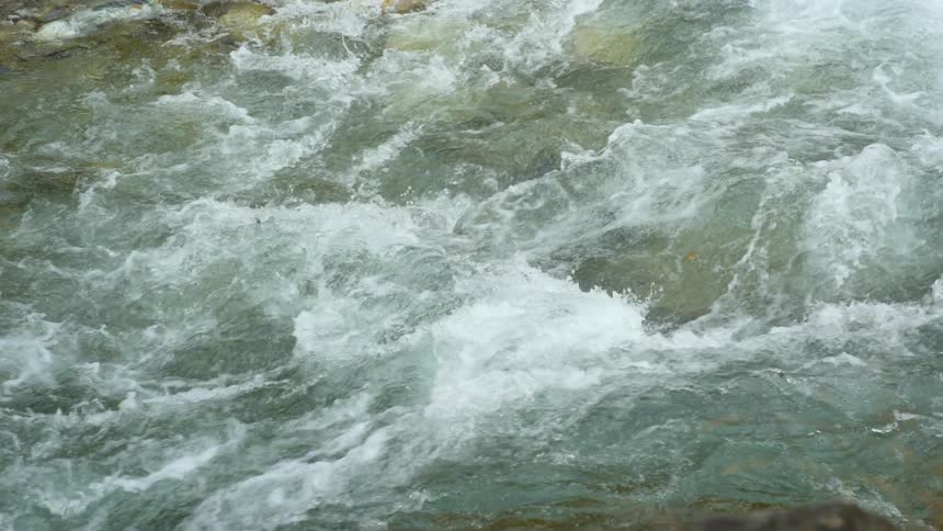 Slow motion footage of the turbulent surface of a river flowing at daytime