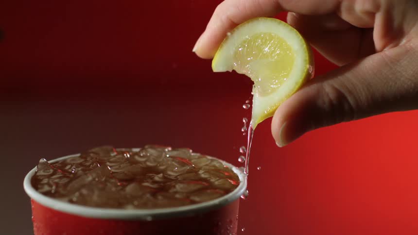 A person squeezes a lemon on their fresh iced tea