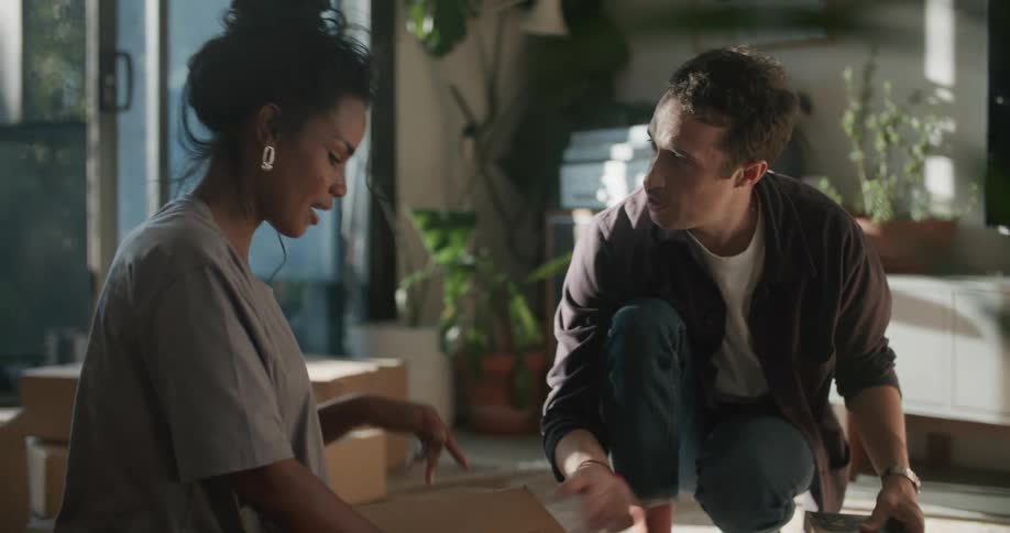 Man and woman talk as they pack books into a cardboard box