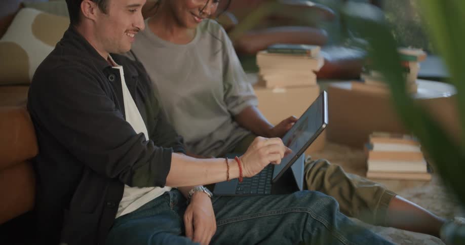 Man and woman are sitting in their house together and looking at a laptop