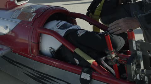 A person is being seated in the race car