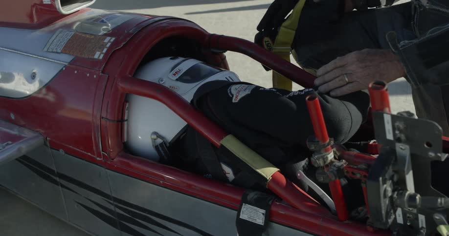 A person is being seated in the race car