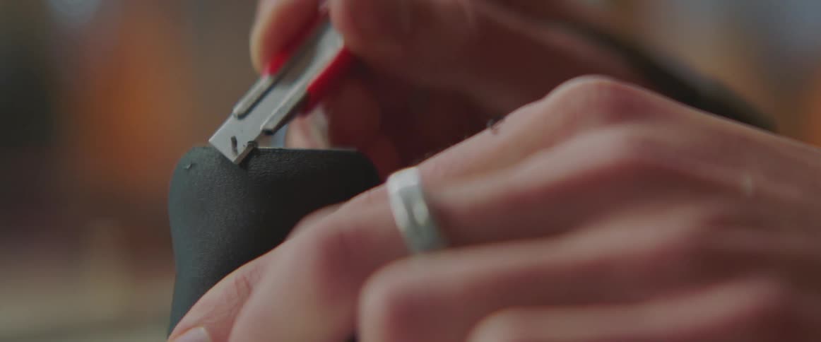 A person cutting the edge of a 3d printed mug base with an xacto knife