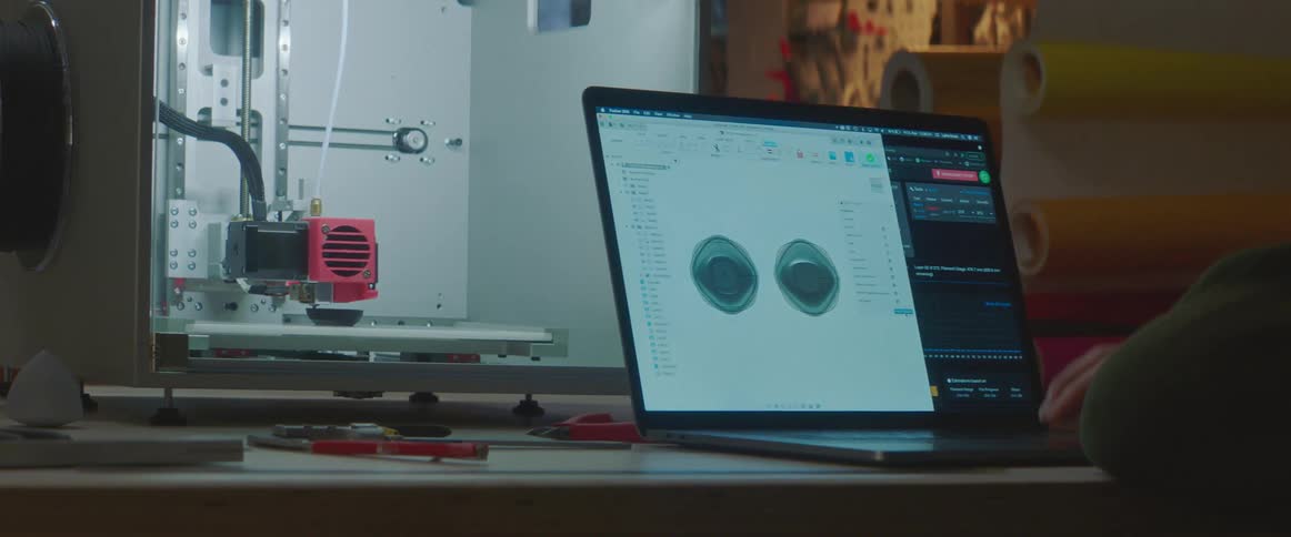 Man designing a cup on a laptop to print on a 3d printer inside a warehouse