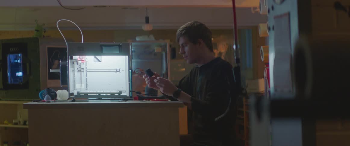 A man examines a small cup while sitting at a table in a lab