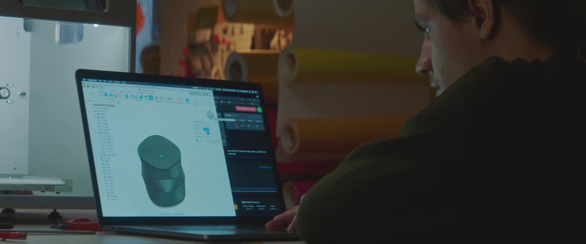 Man with sweater sits at desk works on laptop in lab