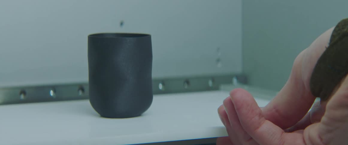 A man pulls a cup out of a 3d printer