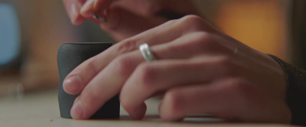 Someone is using a knife to cut the rough edges off the bottom of a cup