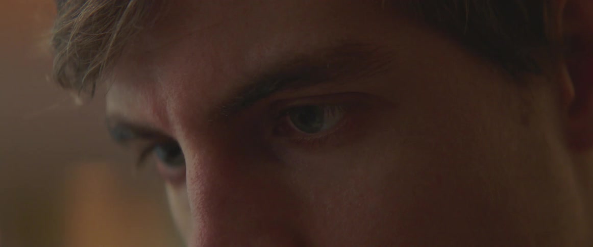 Close up of the eyes of a man focused on a task inside a dimly lit room
