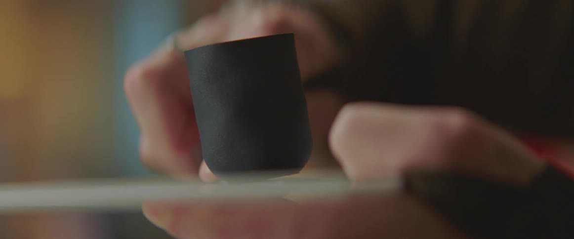A person uses a knife to separate a black 3d printed cup from its base