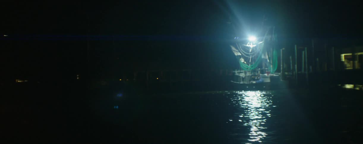 A single light is shining at night on a dock