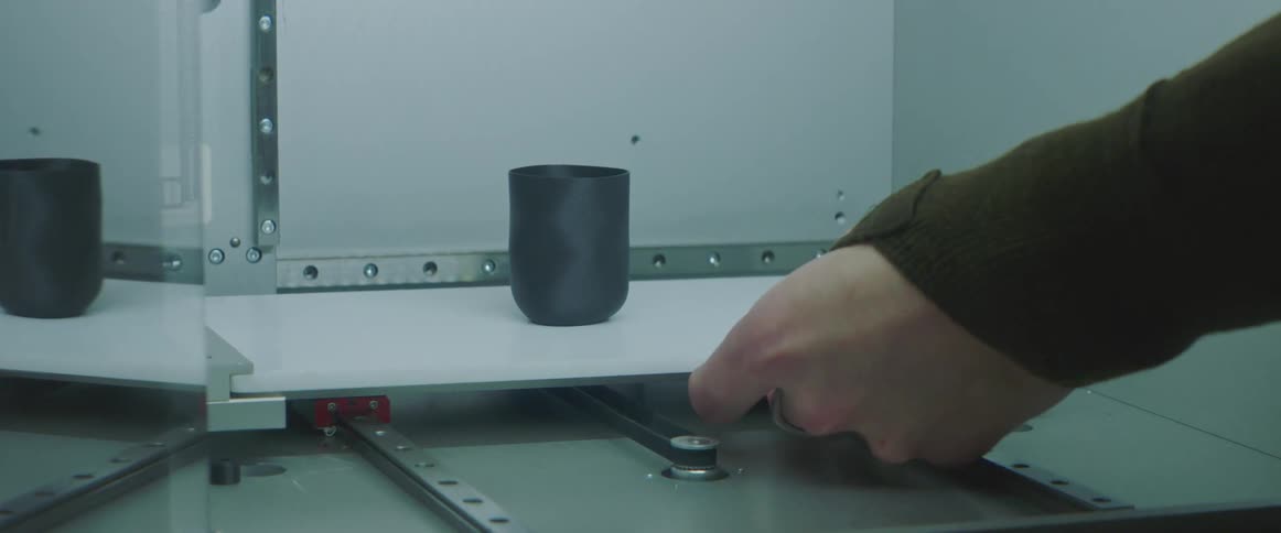 A man takes a mug out of a 3d printer