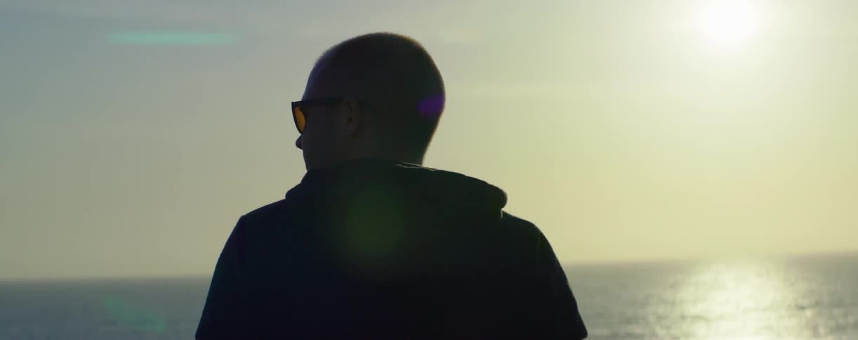 Man wearing sunglasses looks at calm water