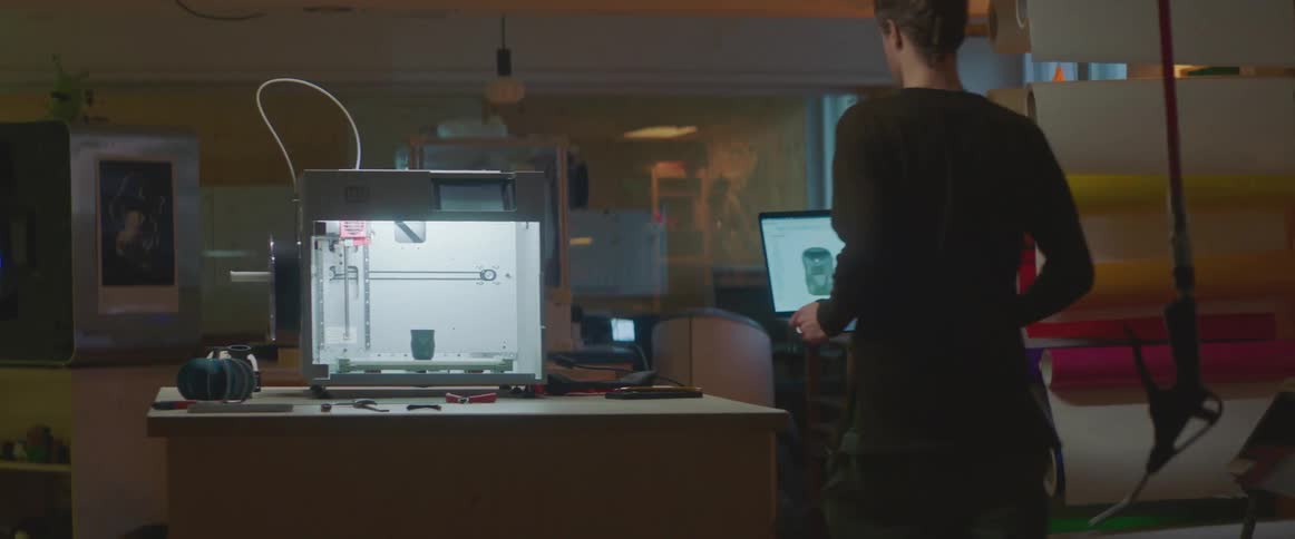 A man gets up from his desk carrying his laptop