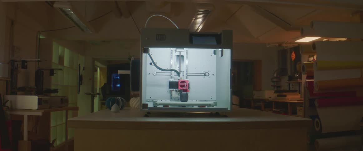 Internal lighting allows 3d chamber to be seen as object is printed in dimly lit workshop