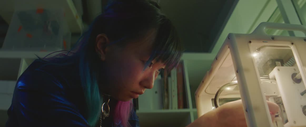 A woman is adjusting a 3d printer
