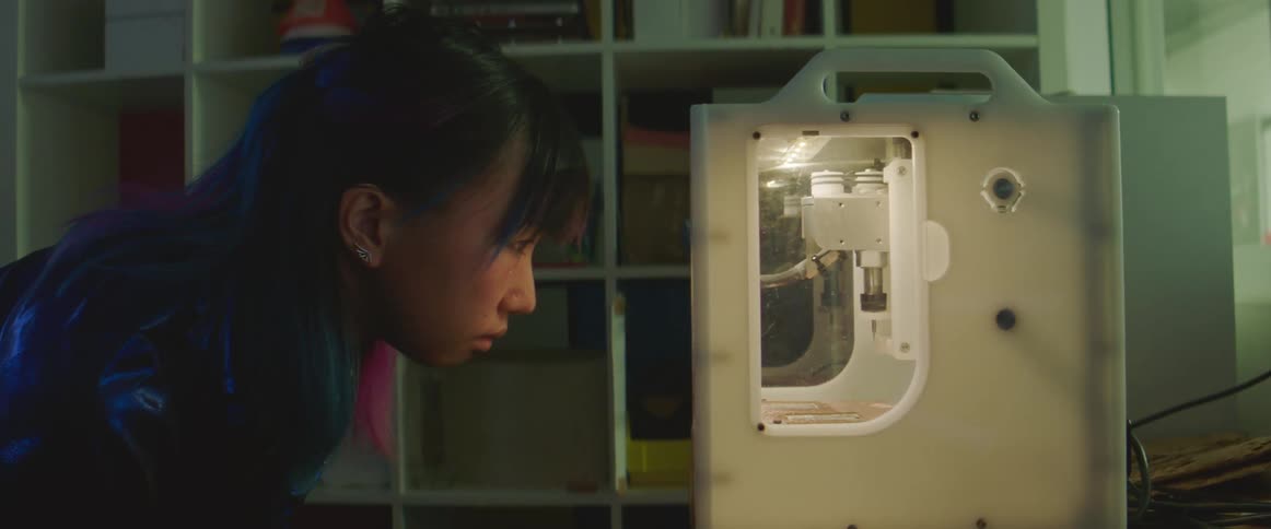A woman watches a 3d printer intently