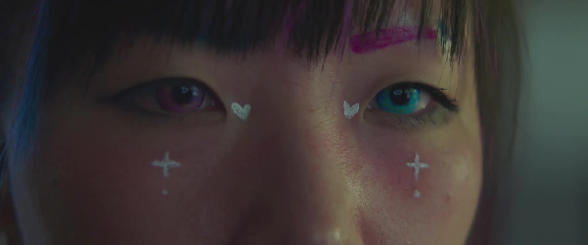 Woman wears face paint and contact lens in two different colors