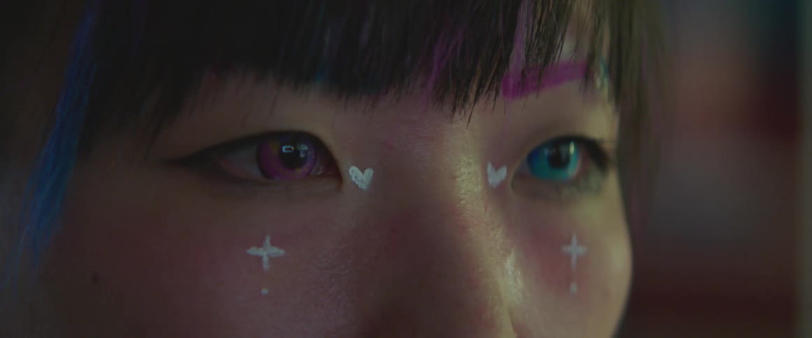 A woman wears different colored contact lenses that match her pink and blue hair