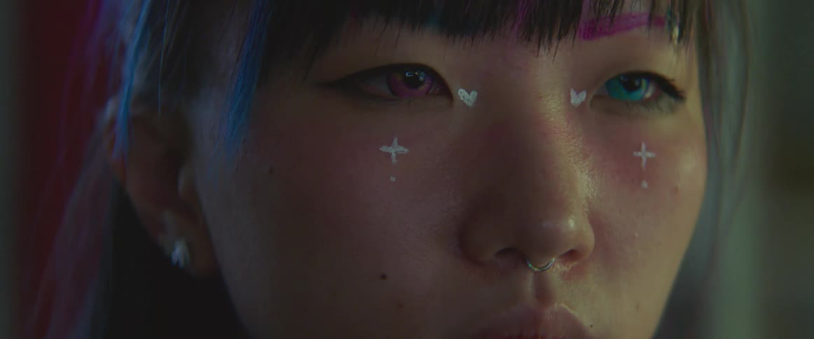 A close up of a teenage girls face with hearts and crosses drawn on her