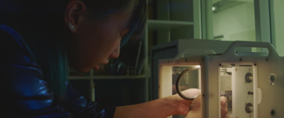 A woman tightens a rod on some equipment