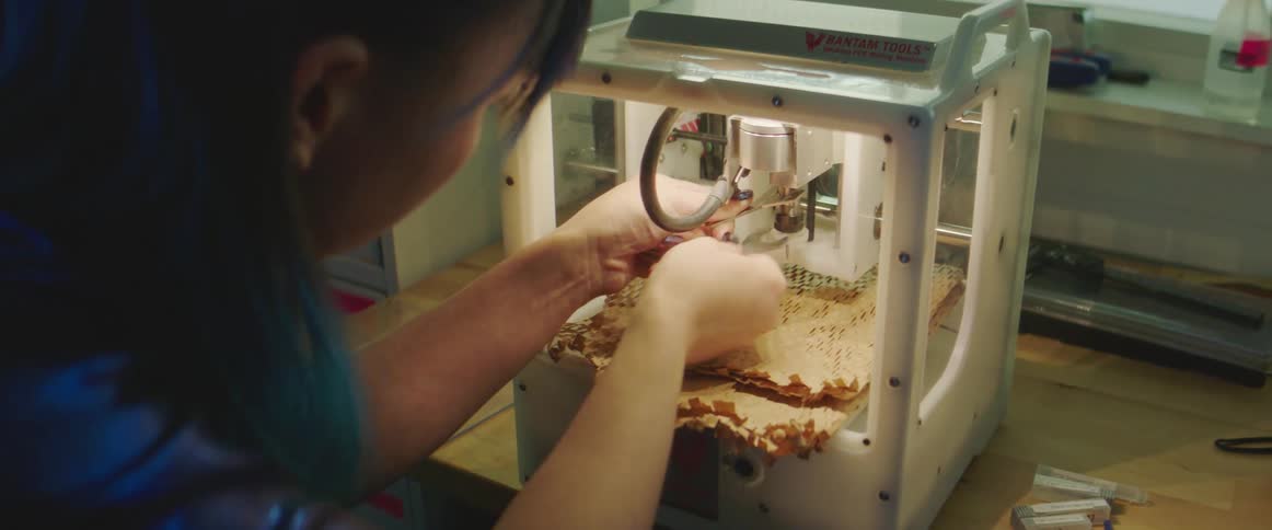 Woman with blue dyed hair works on 3d printer