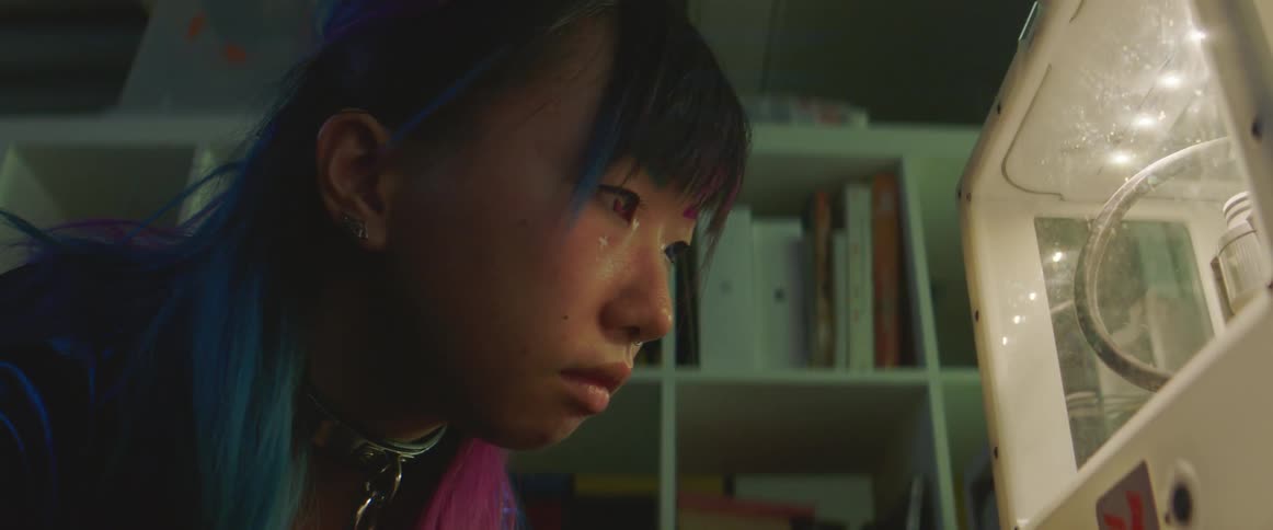 A girl watches a three dimensional printer in her bedroom