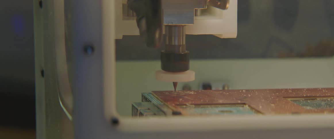 A milling machine carves holes into a circuit board