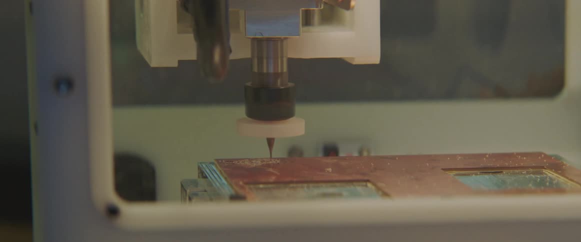 A 3d printing machine is creating an object on a wooden platform