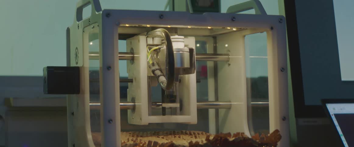 Someone opens the glass door on a 3d printer and works on it with a wrench