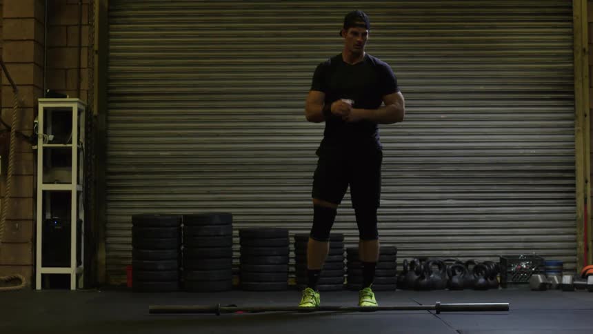 A man prepares to workout in a gym with lots of weights behind him