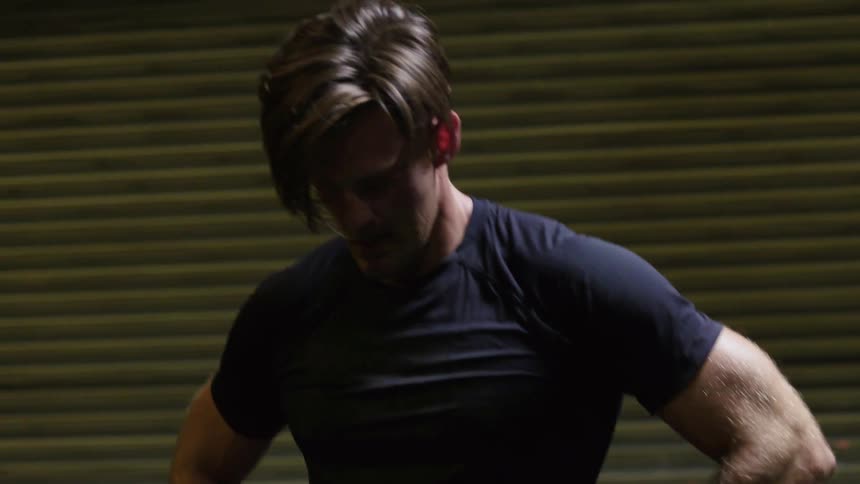 A man walks around with his hands on his hips before wiping his hair