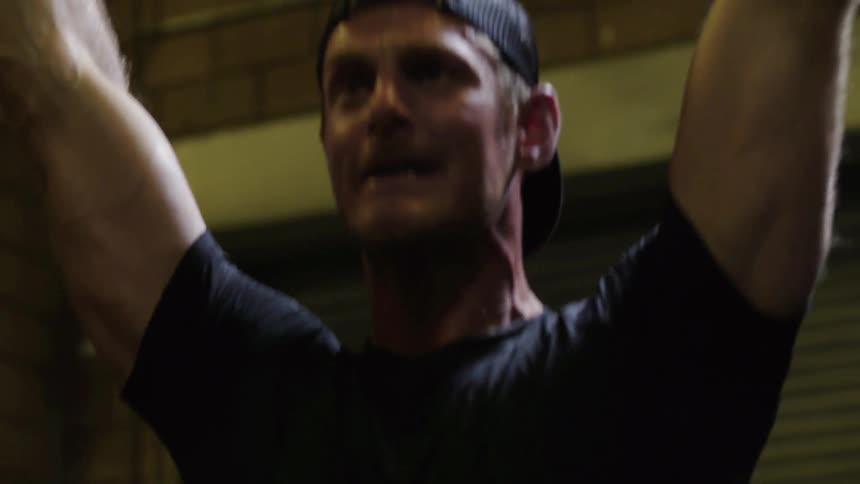 A man shouts as he lifts weights over his head