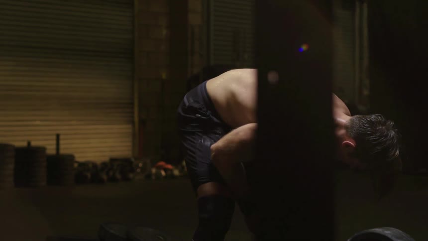 A man takes a breather crouched over in a gym