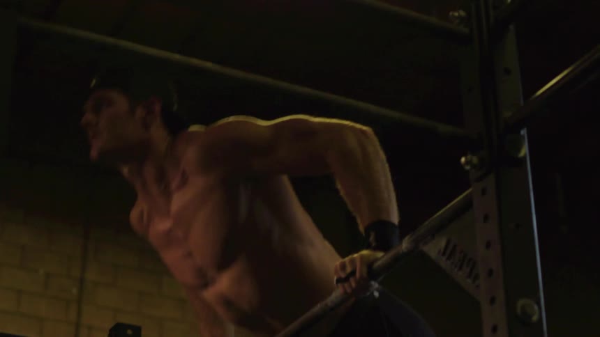 A man is working out on some bars in a gym