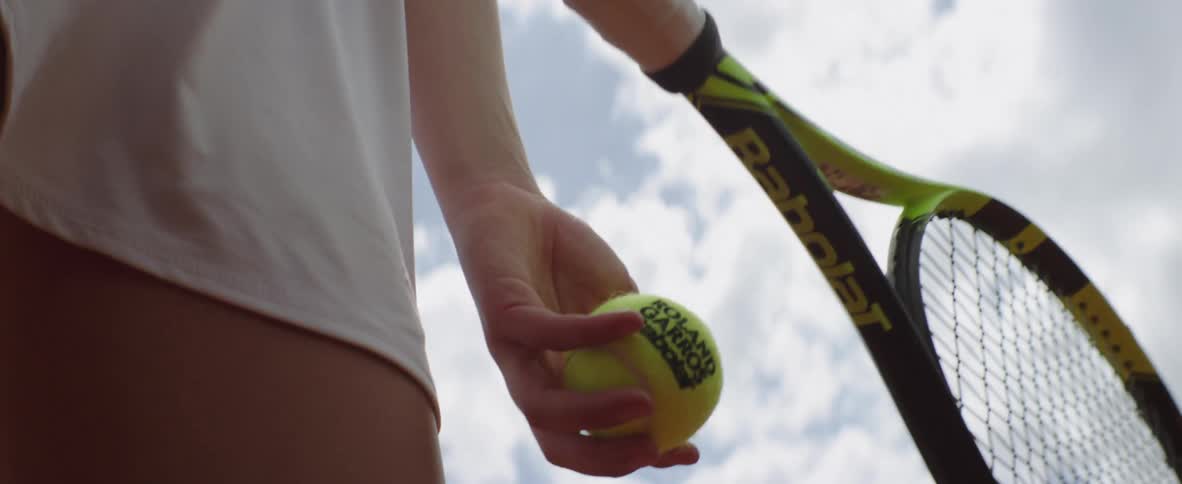A tennis player throws a ball up to serve