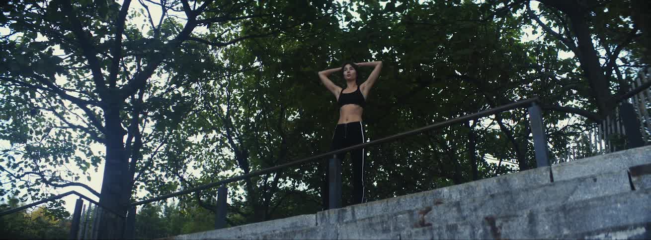 Woman in sports bra and black leggings rests and goes on to jog in public park