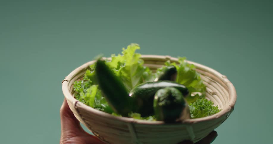 Person holds bowl with lettuce as hot peppers fall into it from above