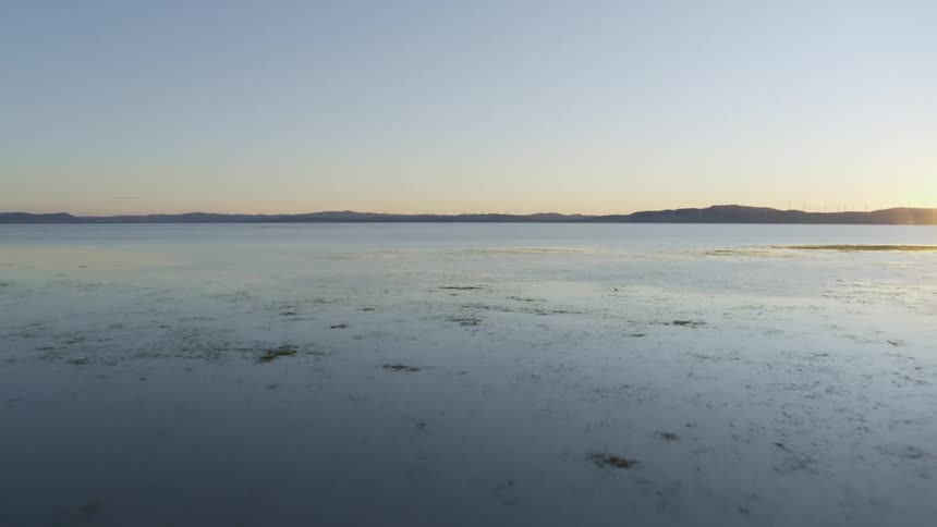 Sunlight reflects on the snow and ice and there are mountains on the horizon