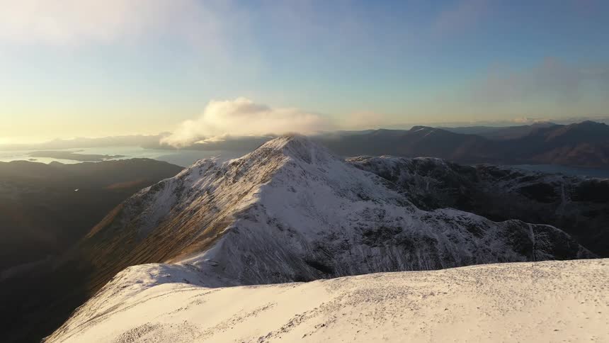 Aerial view of the snow covered slopes of the ridge on a mountain range at morning