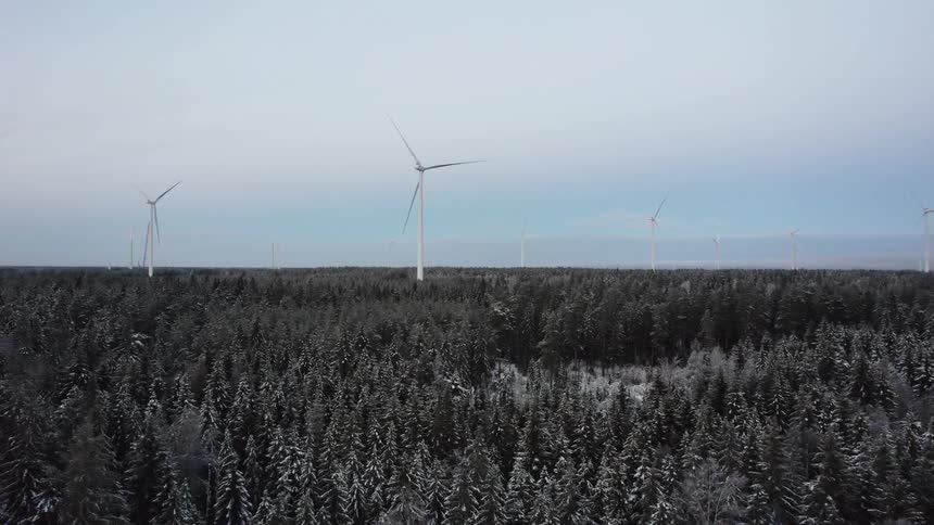 Snow covered forest with wind turbines high above the trees