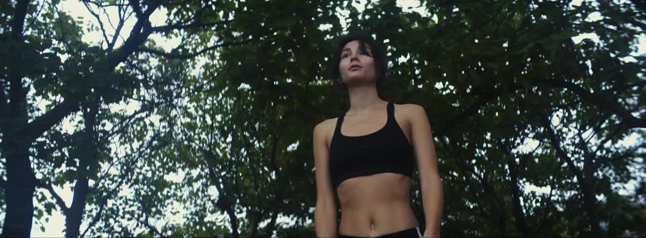 A young woman who is jogging stops to catch her breath and then runs back off