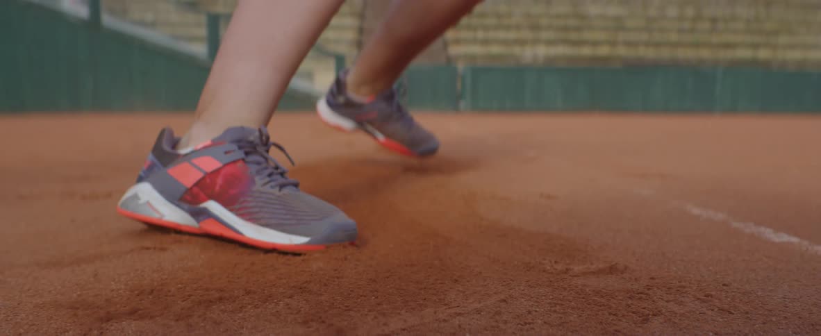 Tennis player runs across court skidding to a stop then moves the other way