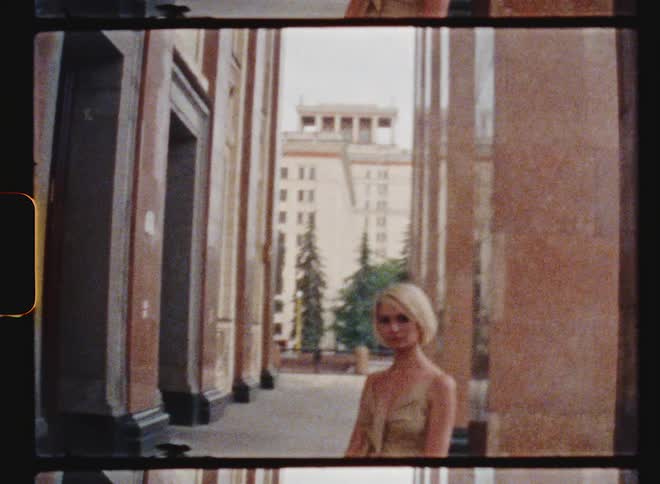 A model poses in front of a column outside a city building
