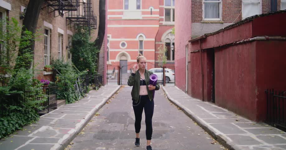 A woman is walking in a city with workout equipment
