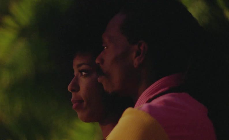 Side profile of male and female dancers with curly hair and braids holding each other