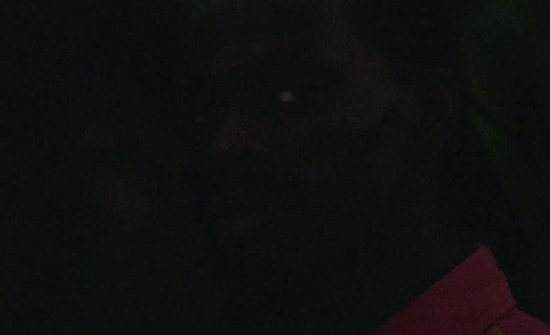 Male dancer with braids and beard faces the camera with eye contact