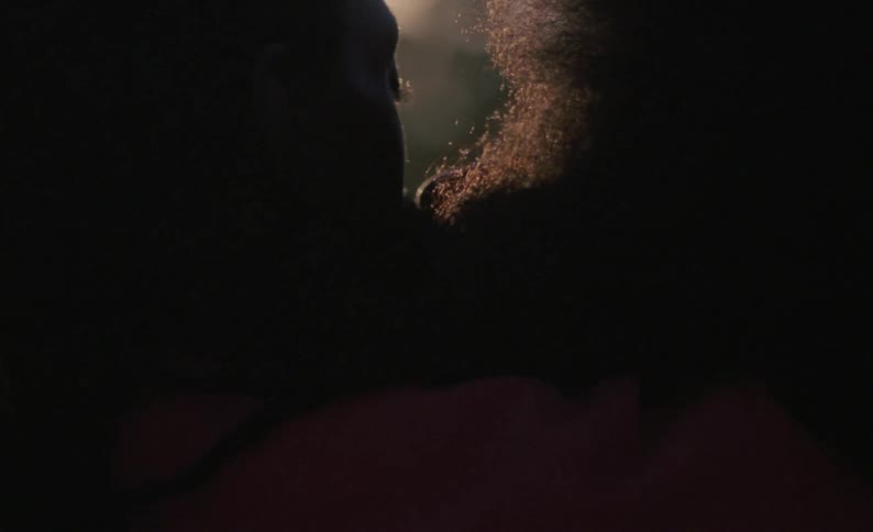 A man and woman kiss passionately while sitting together outdoors during the day