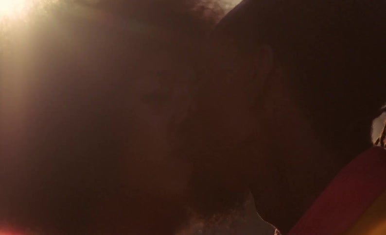 A woman and man kiss while outdoors during the day